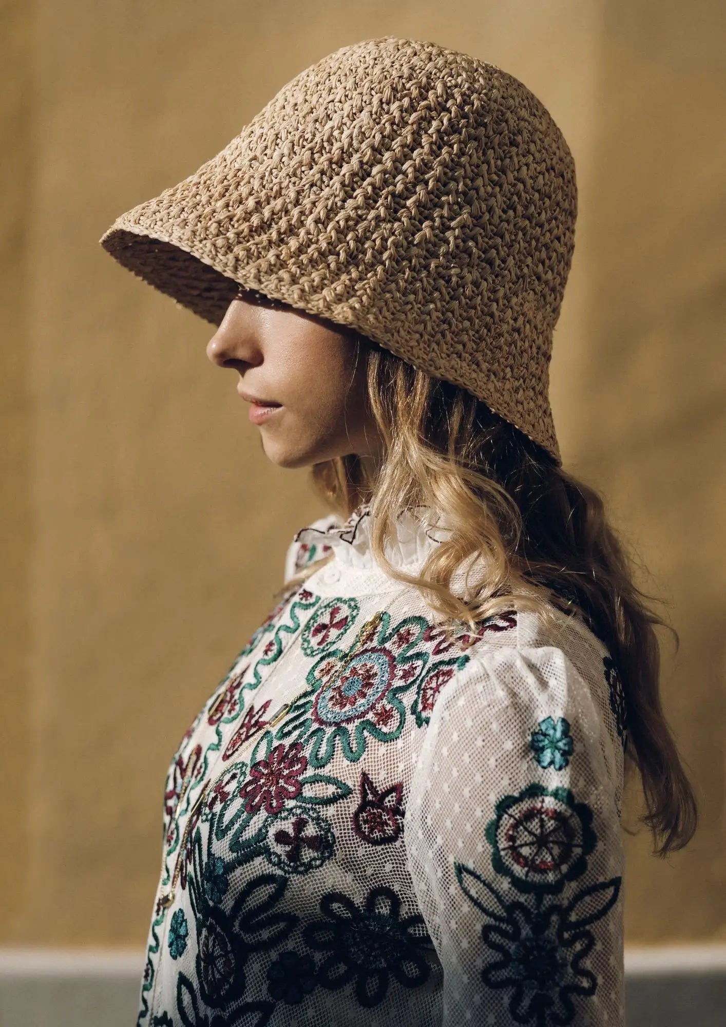 A woven beige bucket hat with a textured, crocheted pattern.
